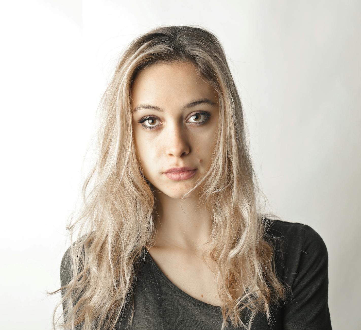 About 7 woman in gray shirt standing beside white wall